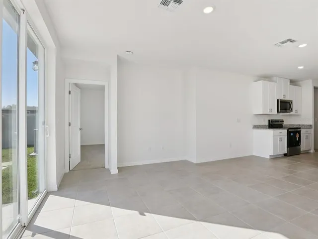 an empty room with kitchen view and a fireplace