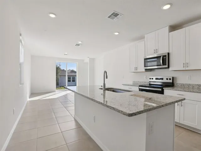 a kitchen with granite countertop a sink and a stove top oven with white cabinets