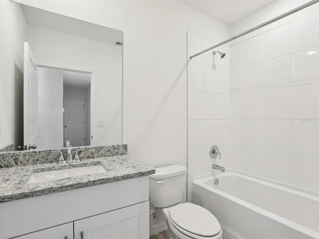 a bathroom with a granite countertop sink toilet mirror and bathtub