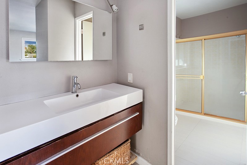 7722 Faust Avenue West Hills, CA 91304 - Photo 13 of 21 Private en suite bathroom with a separate vanity area featuring a wood-grained vanity, integrated basin, and designer lighting. A privacy area includes a glass-enclosed step-in shower and commode.