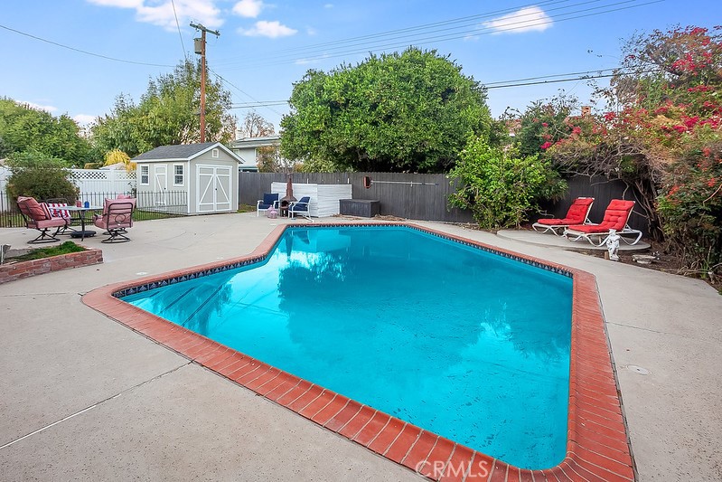 7722 Faust Avenue West Hills, CA 91304 - Photo 20 of 21 The private backyard is designed for entertaining and relaxing, featuring a sparkling inground pool, vibrant flowerbeds, open patio, fenced grassy area, and an oversized storage shed that could serve as an office, creative space, pool house, or more.
