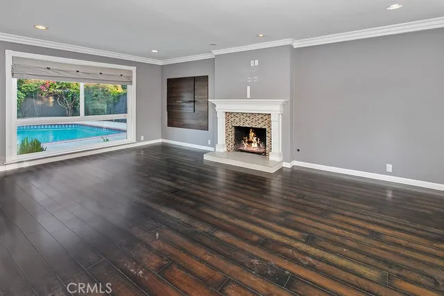 an empty room with wooden floor fireplace and windows