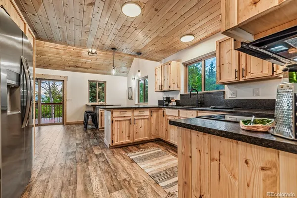 a kitchen with granite countertop a stove a sink and white cabinets