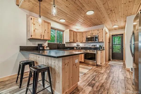 a kitchen with stainless steel appliances granite countertop wooden floors a stove and a refrigerator