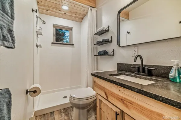 a bathroom with a granite countertop sink a toilet and mirror