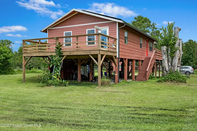 a view of a house with a big yard and large trees