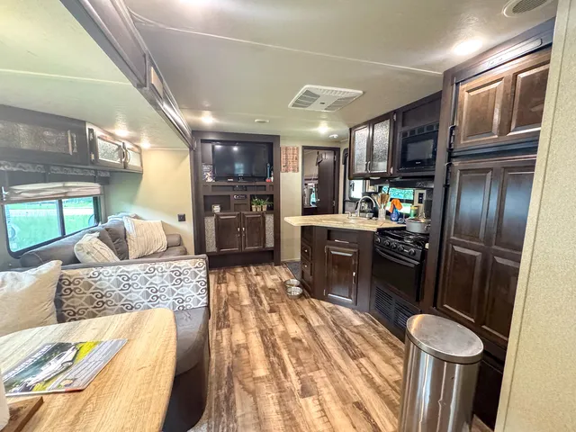 a kitchen with stainless steel appliances granite countertop a refrigerator a stove a sink dishwasher a dining table and chairs with wooden floor