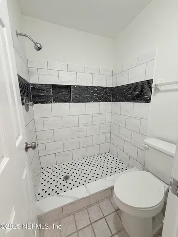 a bathroom with a toilet a window and shower