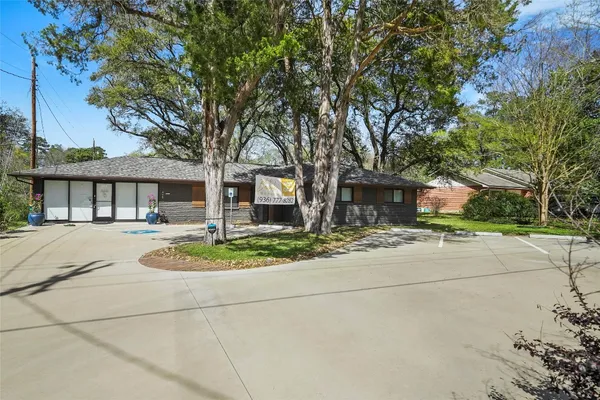 a front view of a house with a garden and trees