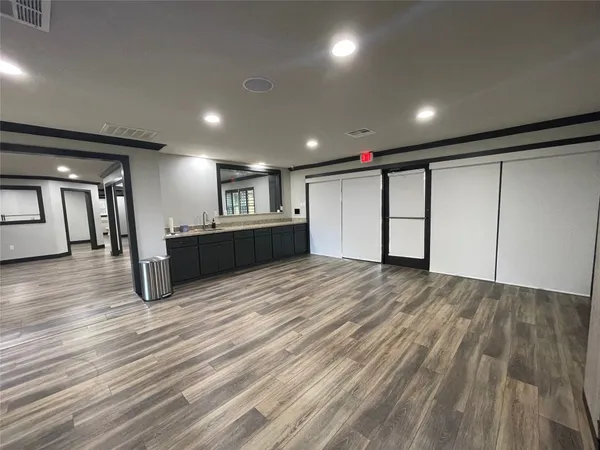a view of an empty room with wooden floor and windows