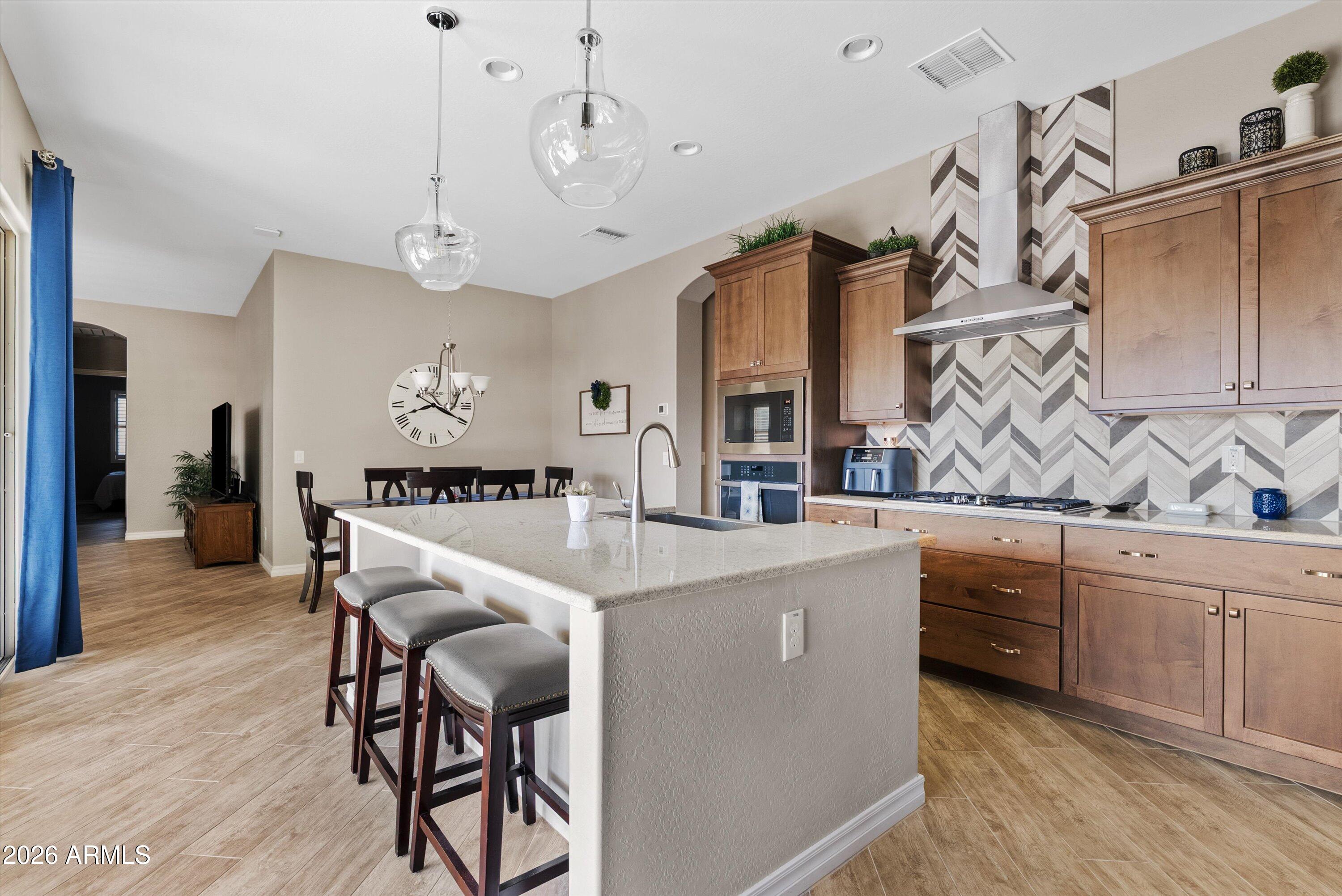 4405 East Dwayne Street Gilbert, AZ 85295 - Photo 13 of 38 a kitchen with stainless steel appliances kitchen island granite countertop a table chairs sink and cabinets