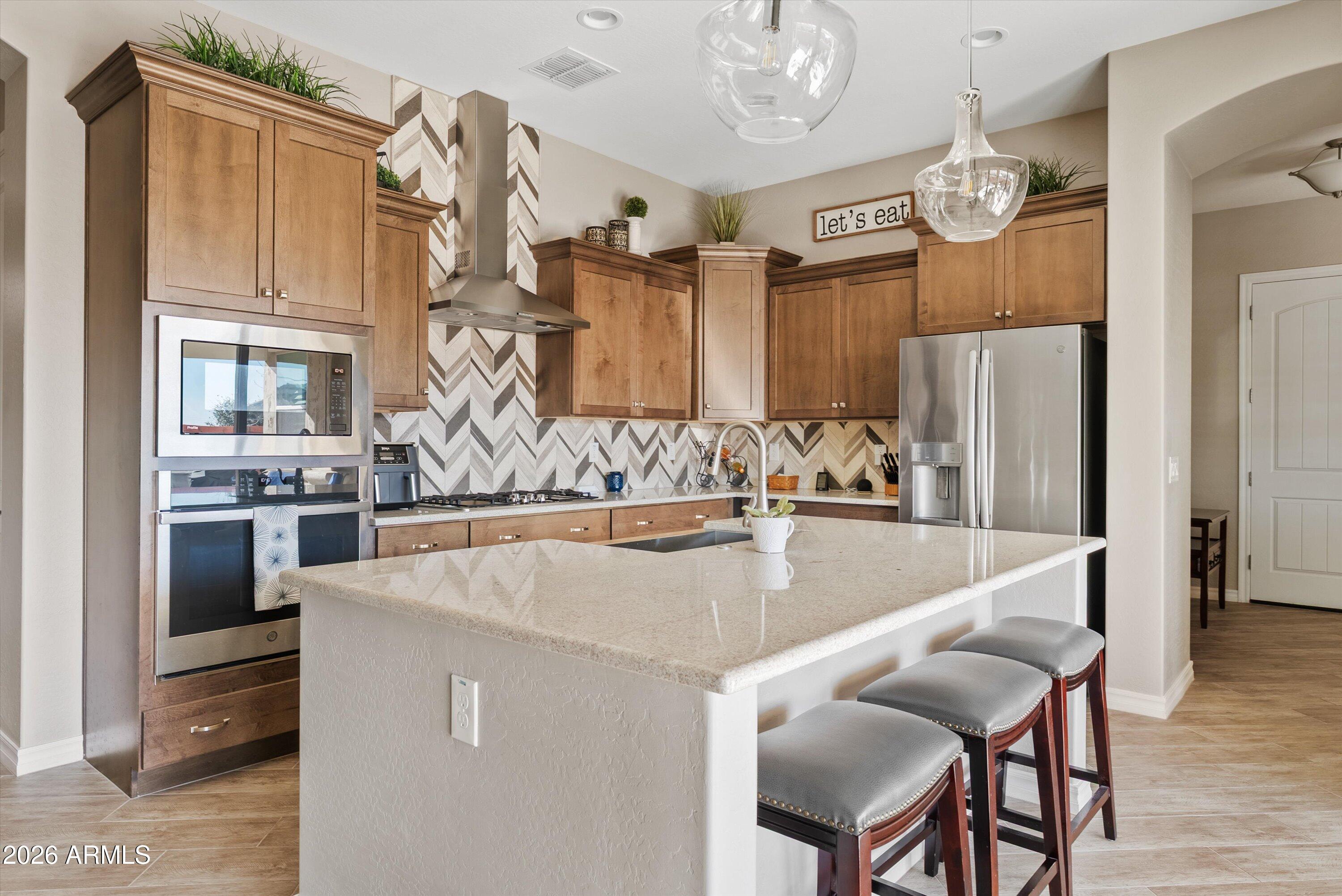 4405 East Dwayne Street Gilbert, AZ 85295 - Photo 14 of 38 a kitchen with stainless steel appliances granite countertop a table chairs and a refrigerator