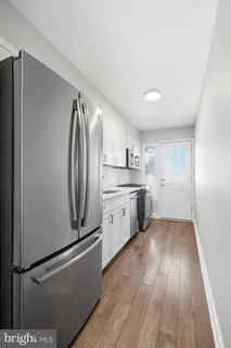 a kitchen with stainless steel appliances a refrigerator a sink and white cabinets