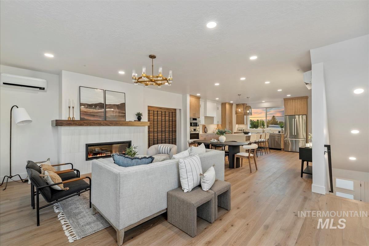3219 West Moore Street Boise, ID 83702 - Photo 3 of 34 Living area featuring recessed lighting, a tiled fireplace, light wood finished floors, a wall unit AC, and a chandelier