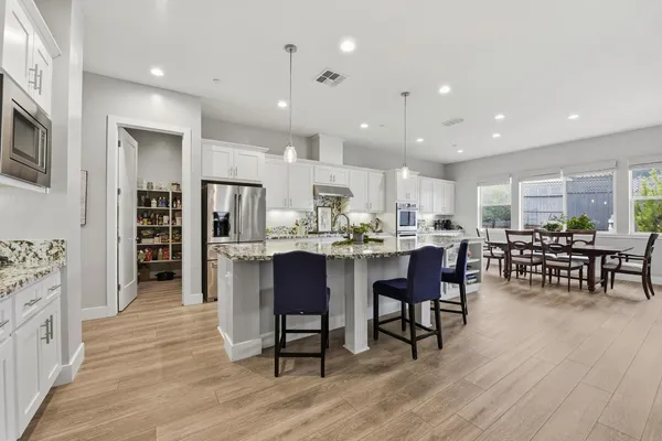 a kitchen with stainless steel appliances kitchen island granite countertop wooden floors and white cabinets