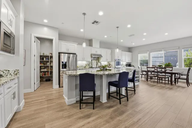 a kitchen with stainless steel appliances kitchen island granite countertop wooden floors and white cabinets
