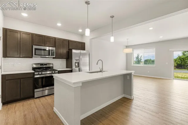 a large kitchen with stainless steel appliances granite countertop a stove a sink and a refrigerator