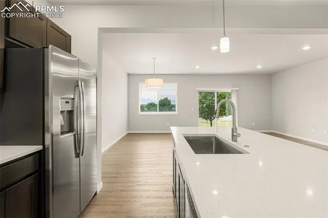 a view of a kitchen with a sink and dishwasher a refrigerator wooden floor