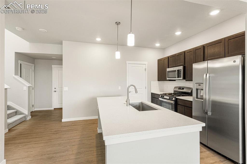 5466 Arden Grove Colorado Springs, CO 80922 - Photo 6 of 35 a kitchen with a sink a refrigerator and a stove top oven with wooden floor