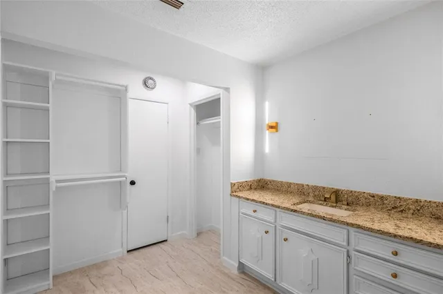 a bathroom with a granite countertop sink and white cabinets
