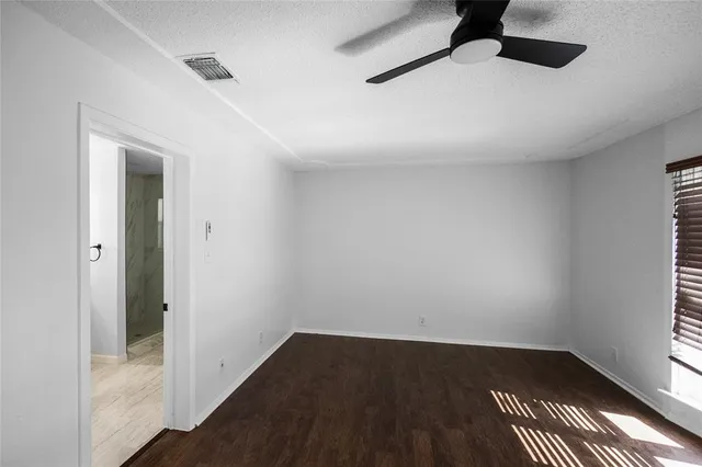 an empty room with a hardwood and ceiling fan