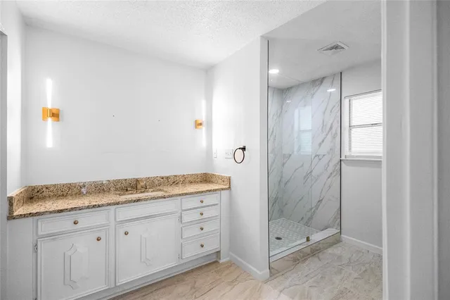 a bathroom with a granite countertop sink and shower