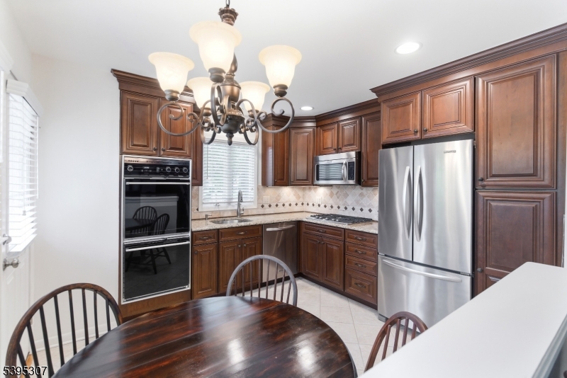 2286 Stocker Lane Scotch Plains, NJ 07076 - Photo 10 of 27 a kitchen with stainless steel appliances granite countertop a refrigerator a stove a sink dishwasher a dining table and chairs with wooden floor