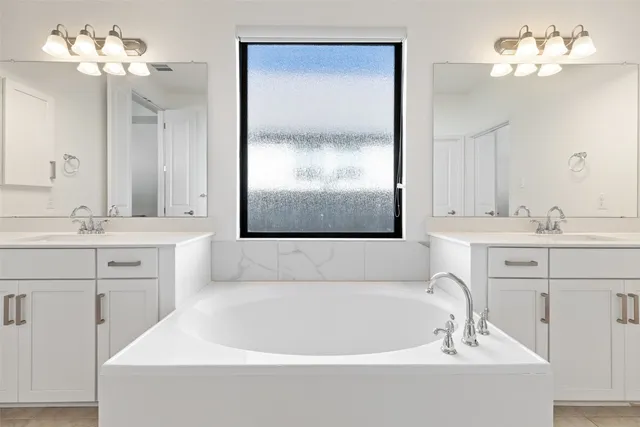 a bathroom with a bathtub a double vanity sink and a mirror