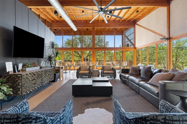 a living room with furniture a flat screen tv and a floor to ceiling window