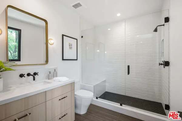 a bathroom with a sink a toilet a shower and a mirror