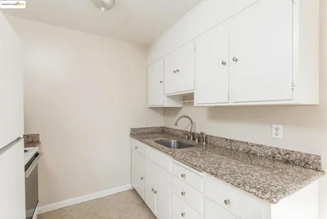 a kitchen with white cabinets and a window