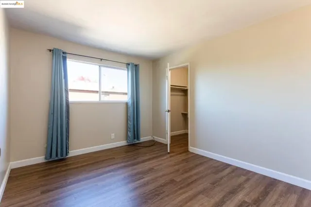 an empty room with wooden floor closet and windows