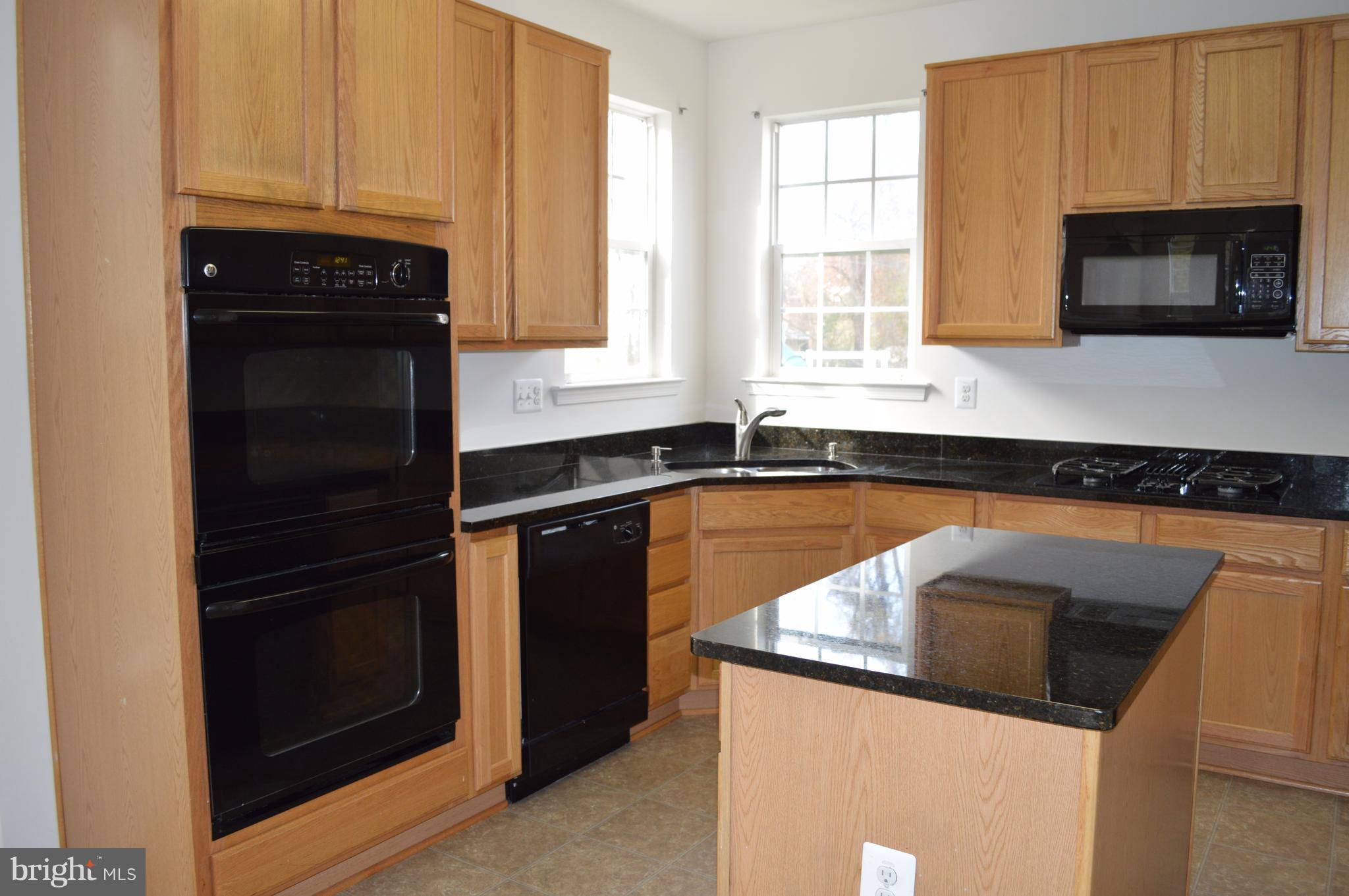 6500 Clarington Road Baltimore, MD 21209 - Photo 7 of 30 a kitchen with granite countertop a refrigerator stove and microwave