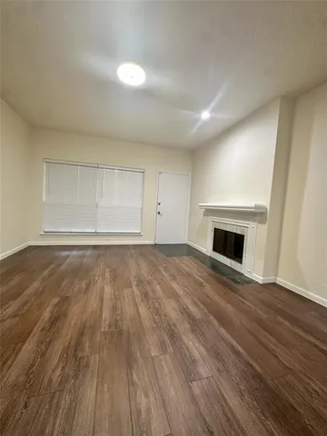 a view of empty room with wooden floor and fireplace