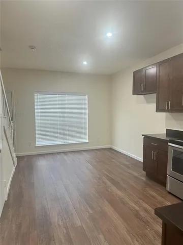 an empty room with wooden floor cabinet and windows