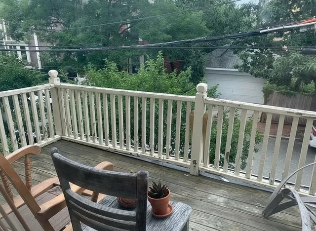 a balcony with wooden floor table and chairs