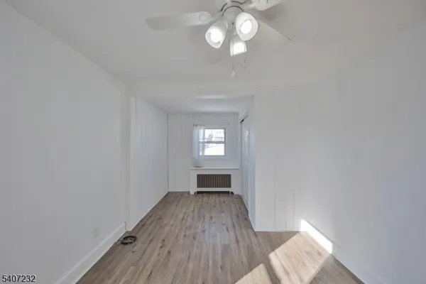 a view of wooden floor and a chandelier fan in a room
