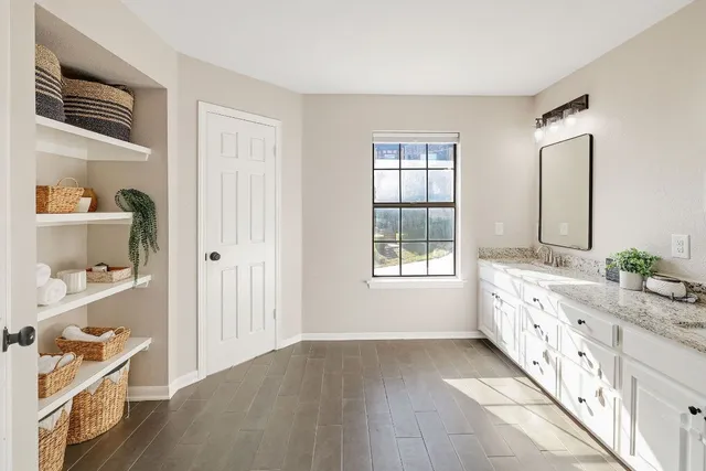 a bathroom with granite countertop a double vanity sink a window and a bathtub