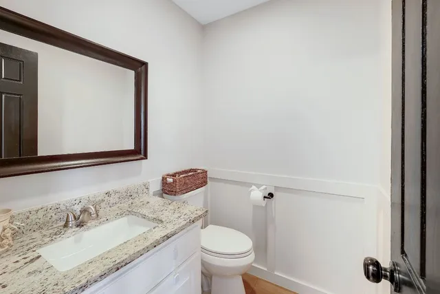 a bathroom with a granite countertop toilet sink and mirror