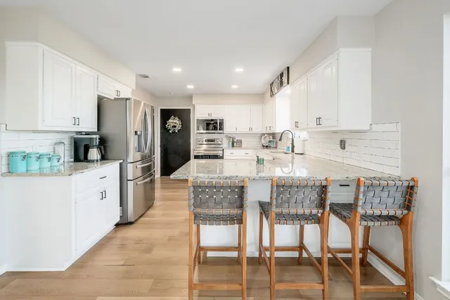 a kitchen with stainless steel appliances kitchen island granite countertop a refrigerator and cabinets