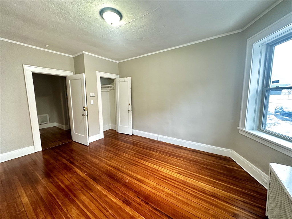 577 Pleasant Street, Unit 1L Holyoke, MA 01040 - Photo 15 of 24 a view of an empty room with wooden floor and a window