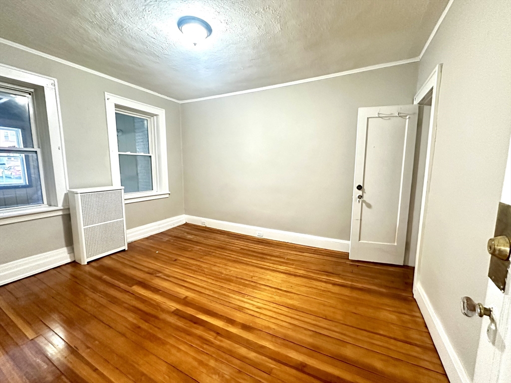 577 Pleasant Street, Unit 1L Holyoke, MA 01040 - Photo 18 of 24 an empty room with wooden floor and windows