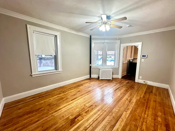 a view of an empty room with window and wooden floor