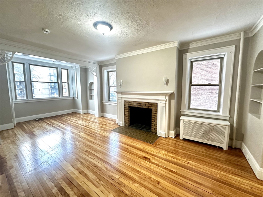 577 Pleasant Street, Unit 1L Holyoke, MA 01040 - Photo 10 of 24 an empty room with wooden floor fireplace and windows