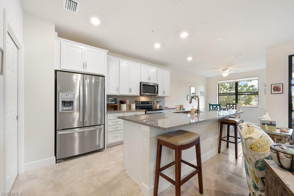 5698 Mayflower Way, Unit 403 Ave Maria, FL 34142 - Photo 9 of 27 a kitchen with stainless steel appliances granite countertop a refrigerator a stove a sink a dining table and chairs