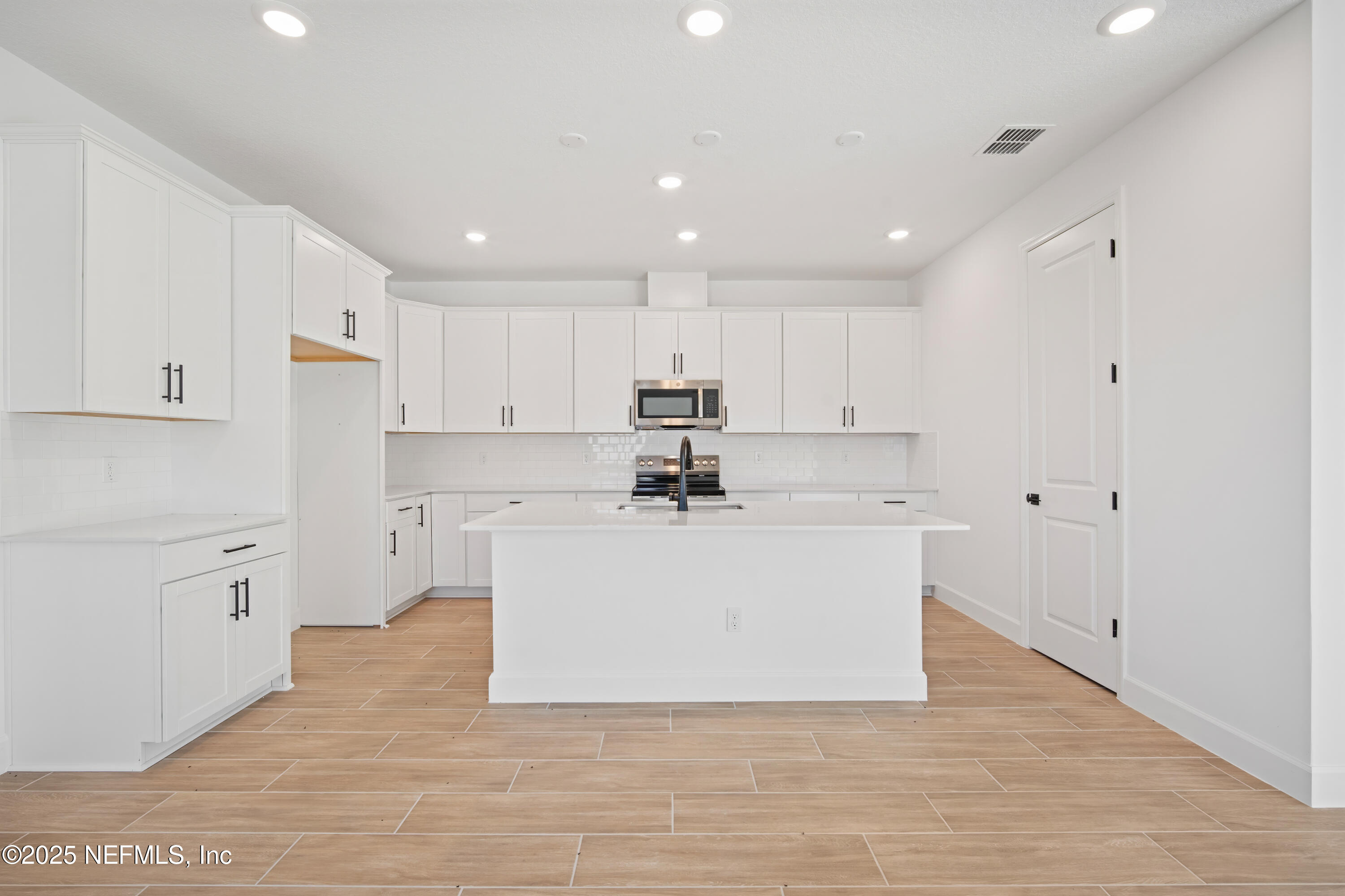 9253 Players Drive Weeki Wachee, FL 34613 - Photo 18 of 30 a large white kitchen with kitchen island a sink a stove a refrigerator and white cabinets