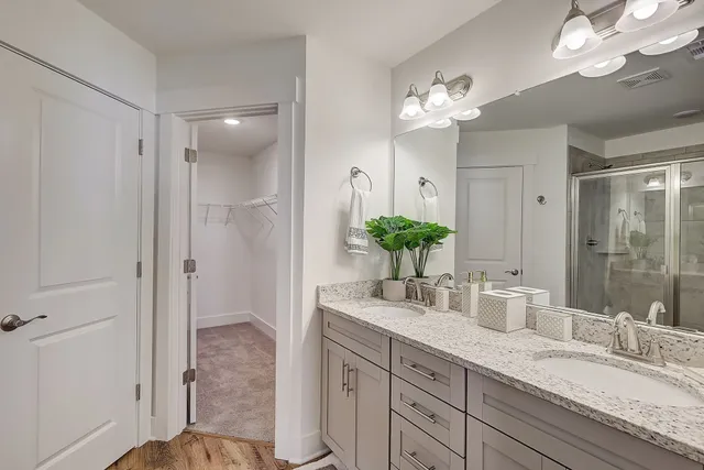 a bathroom with a granite countertop double vanity sink and a mirror