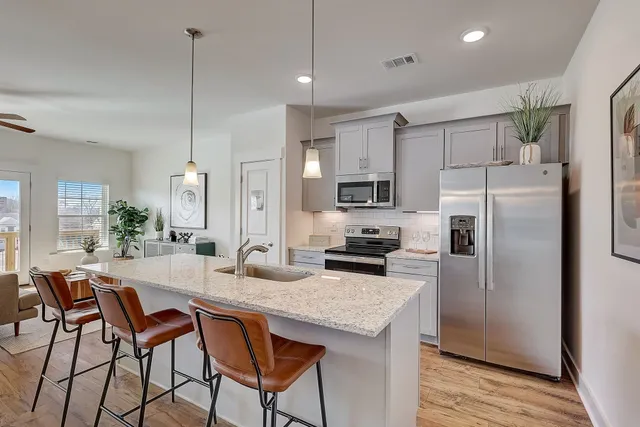 a kitchen with granite countertop a table chairs refrigerator and microwave