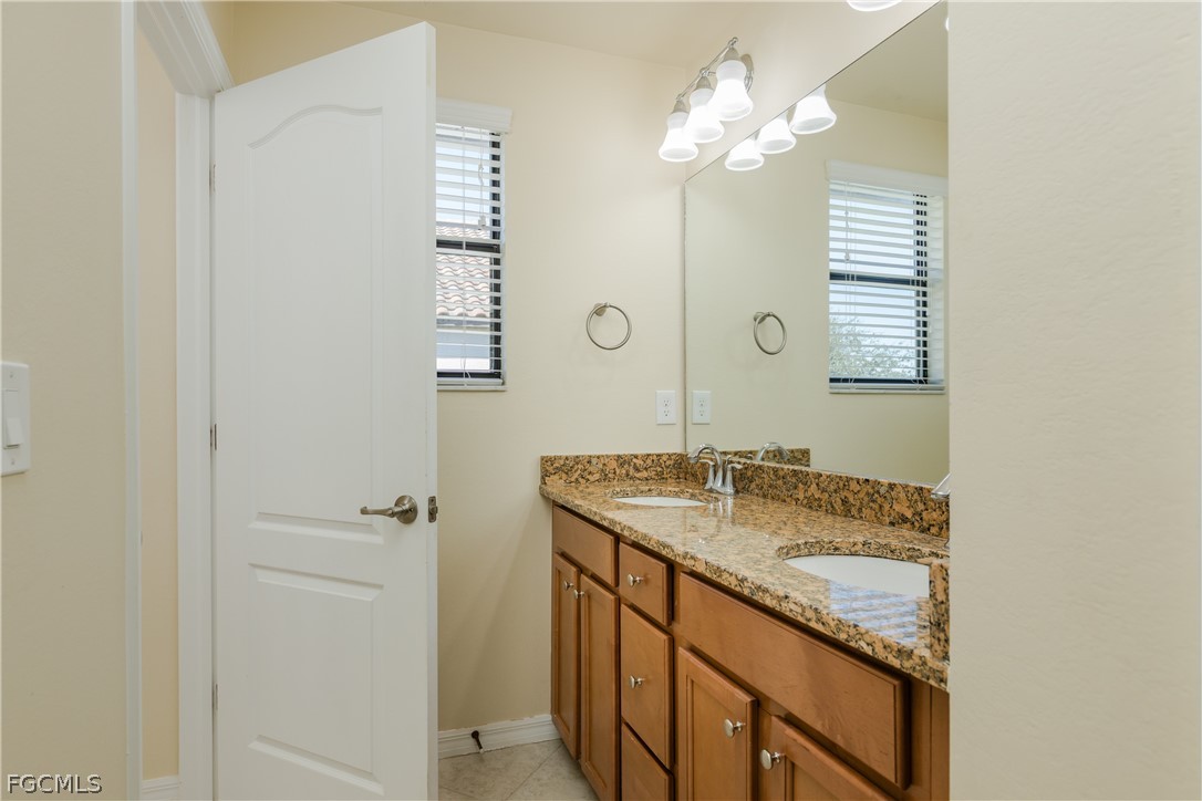12906 Pastures Way Fort Myers, FL 33913 - Photo 27 of 44 a bathroom with a granite countertop sink a mirror and a shower