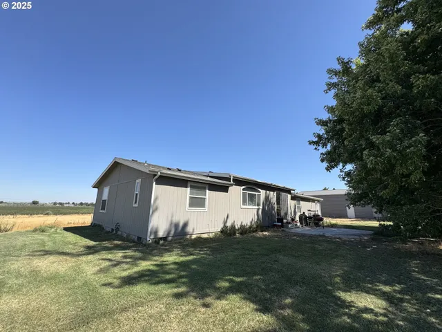 a view of a white house with a big yard and large trees